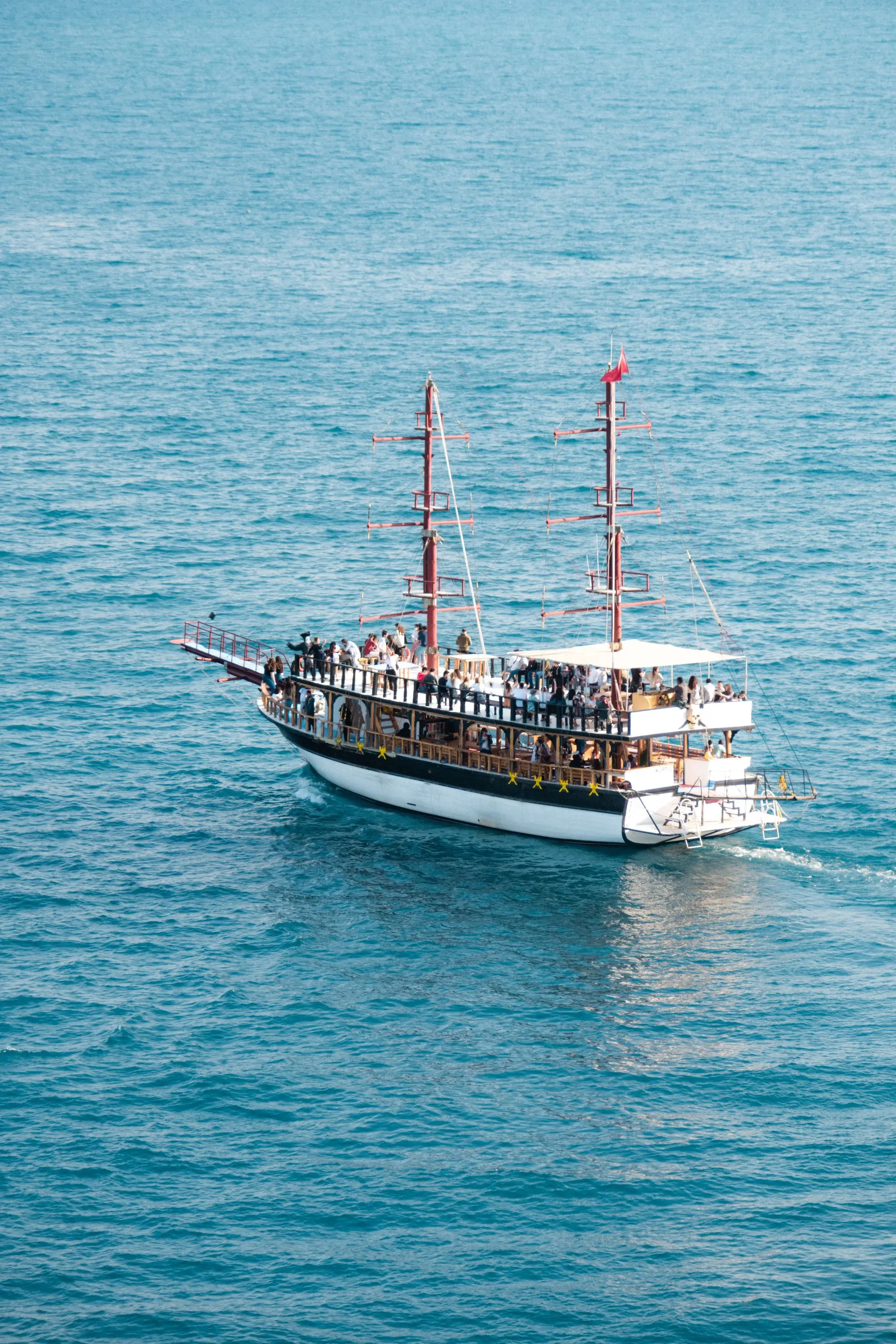 A tour boat full of guests on open blue water, seen from above