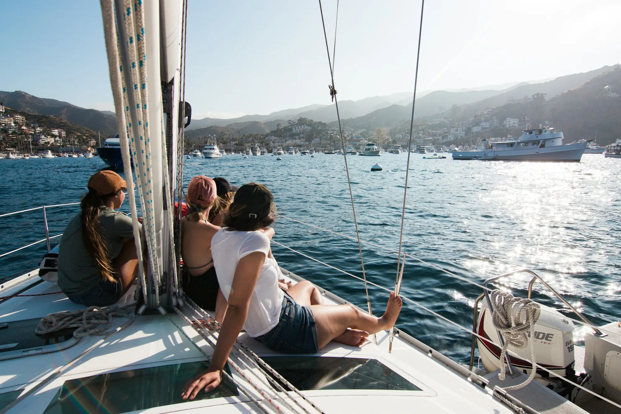 Friends relaxing on the bow of a sailboat in a sunny harbor