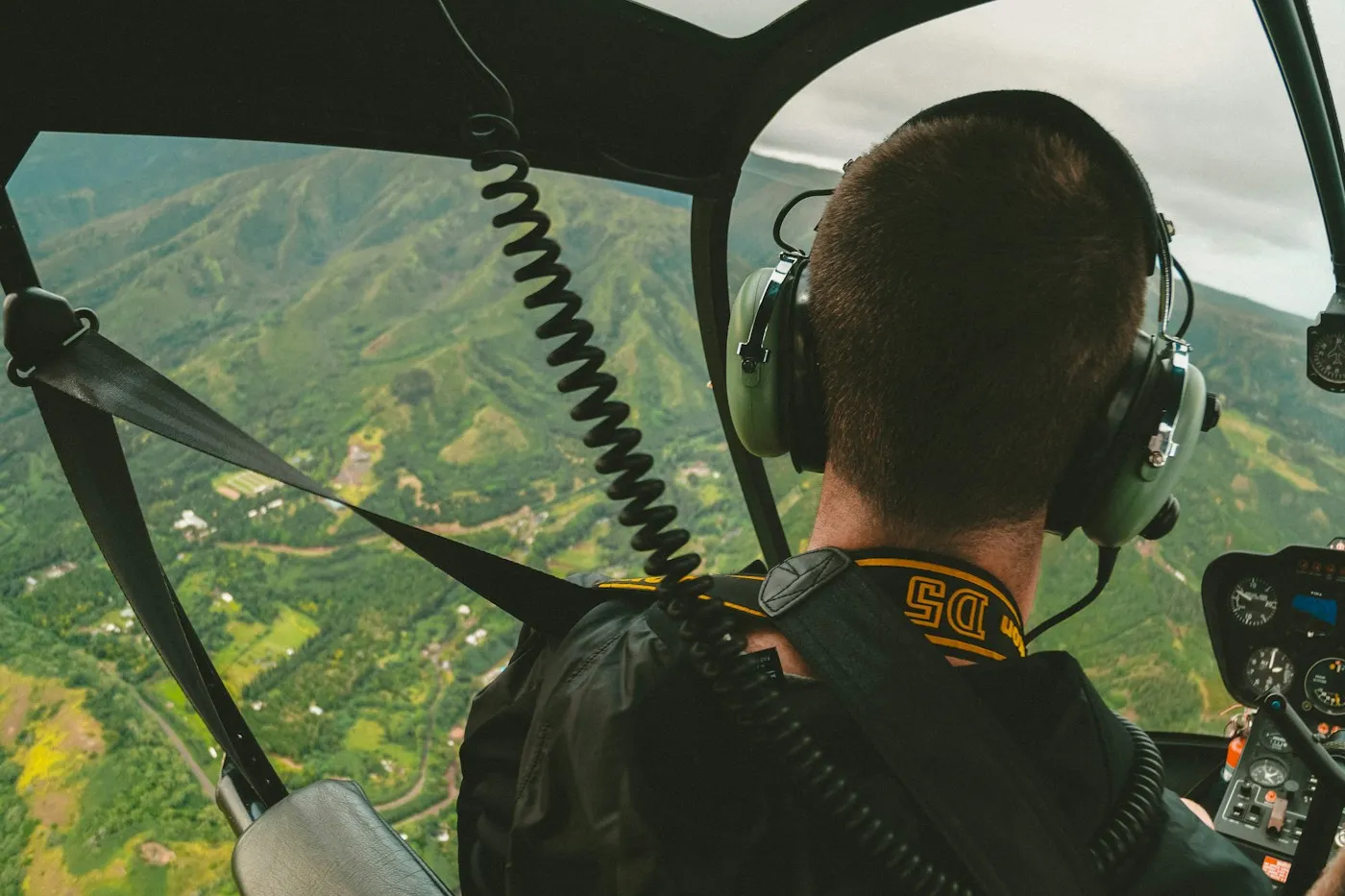 A guest's view from a helicopter cockpit over a green ridge