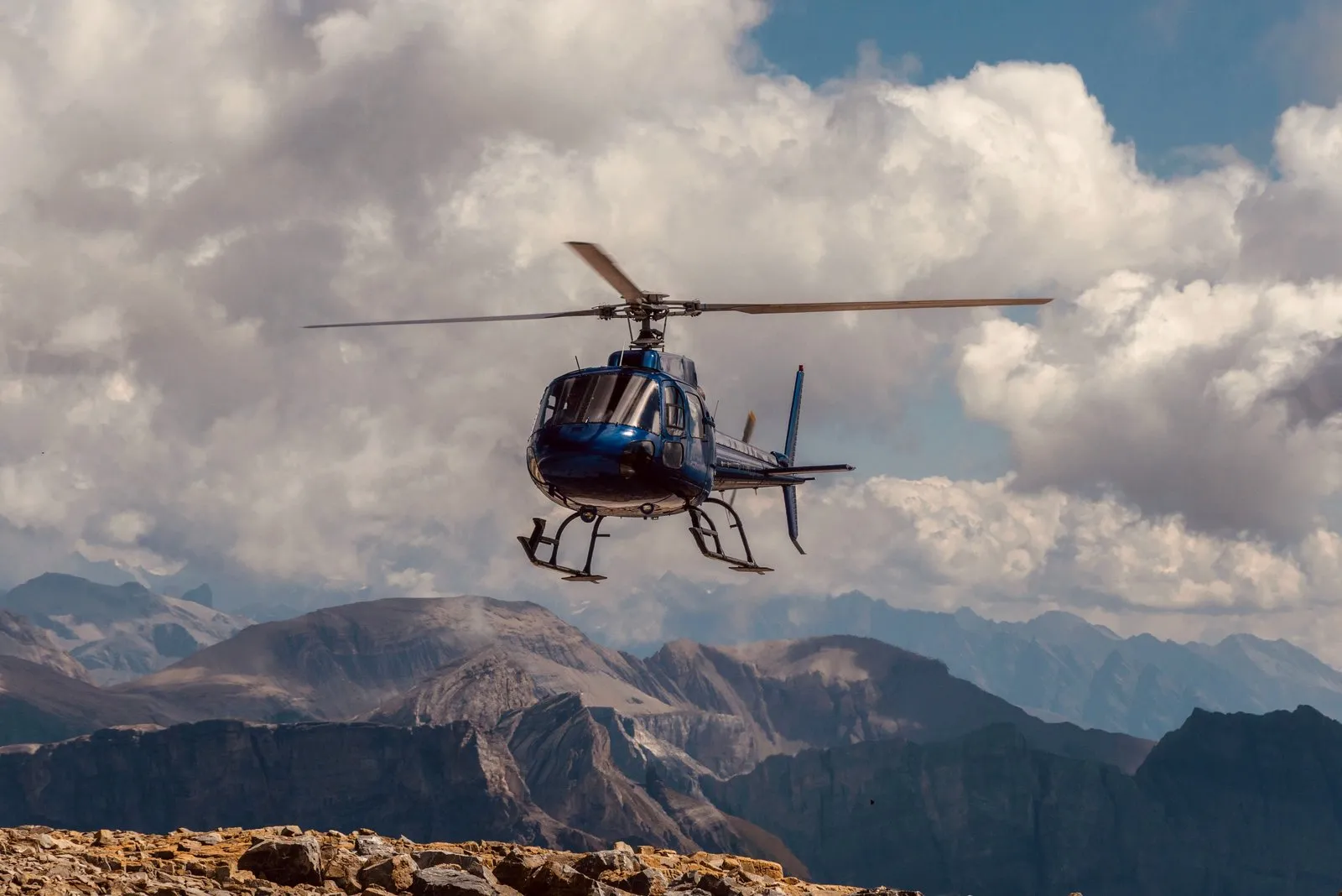 A tour helicopter in flight over mountains